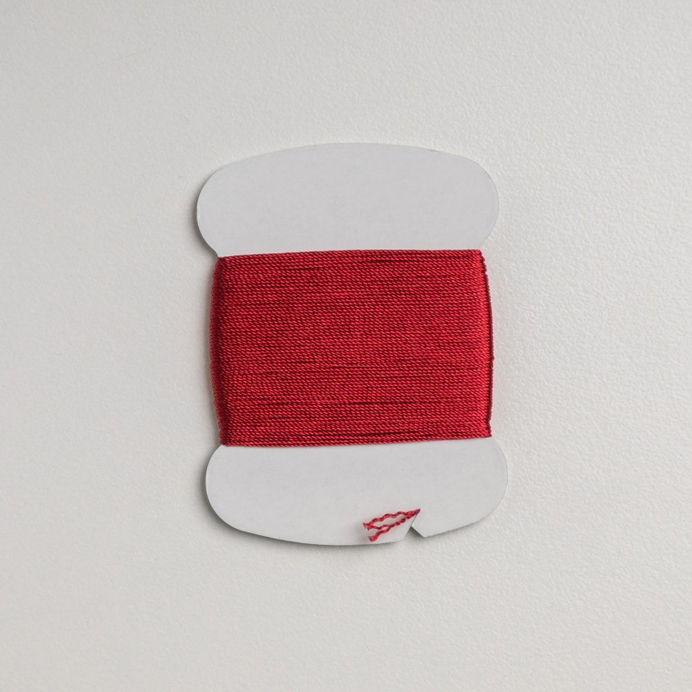 A spool of vibrant red silk thread